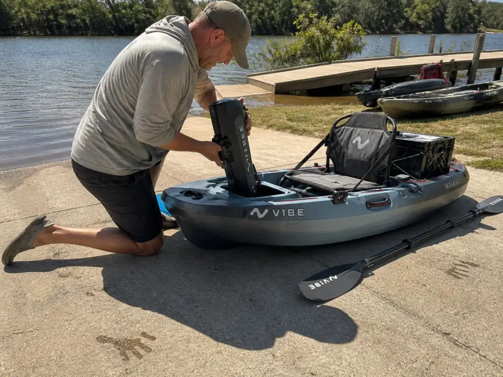 Angler dropping a pedal drive into a fishing kayak on a boat ramp