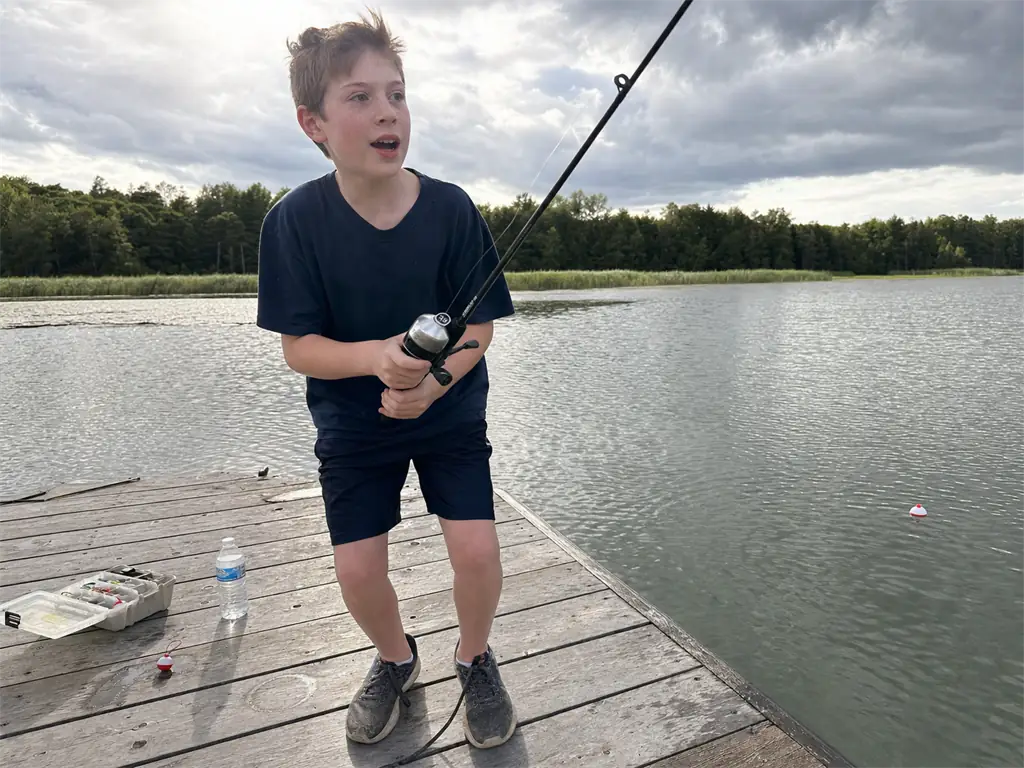 Beginner holding a spincast combo on a dock, the easiest fishing rod type to start with