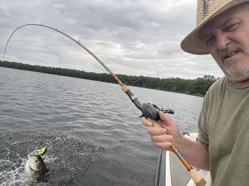 Fiberglass casting rod bent deep against a bass hooked on a treble-hooked squarebill crankbait