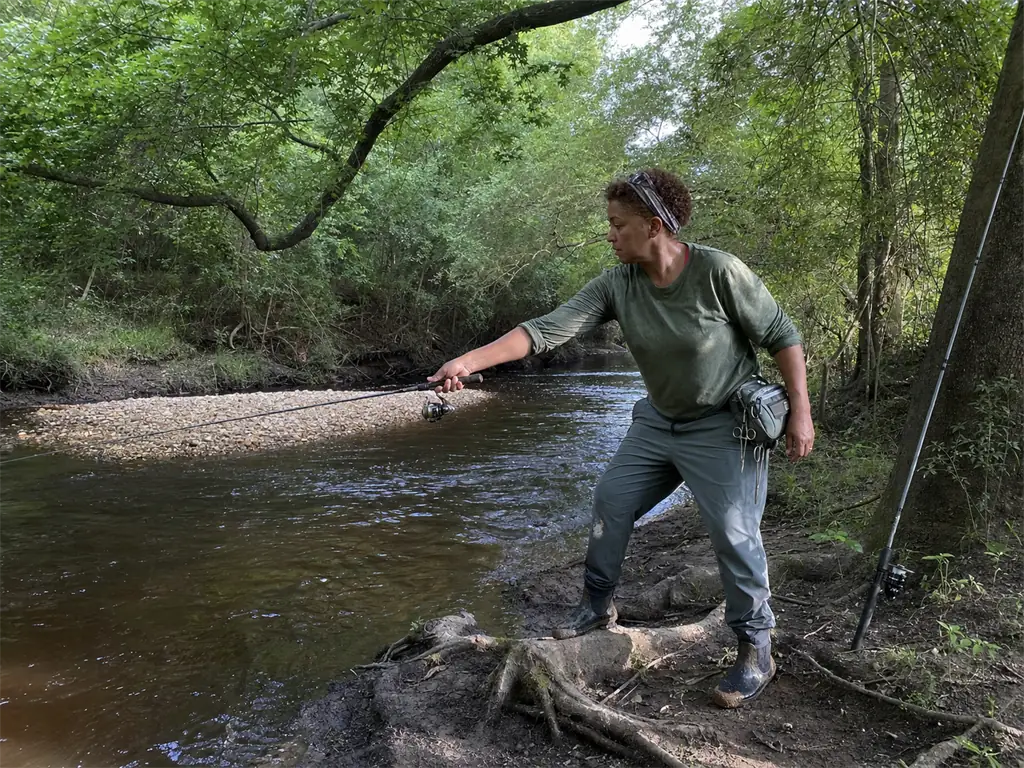 Angler casting a short rod on a tight overgrown creek bank where rod length matters
