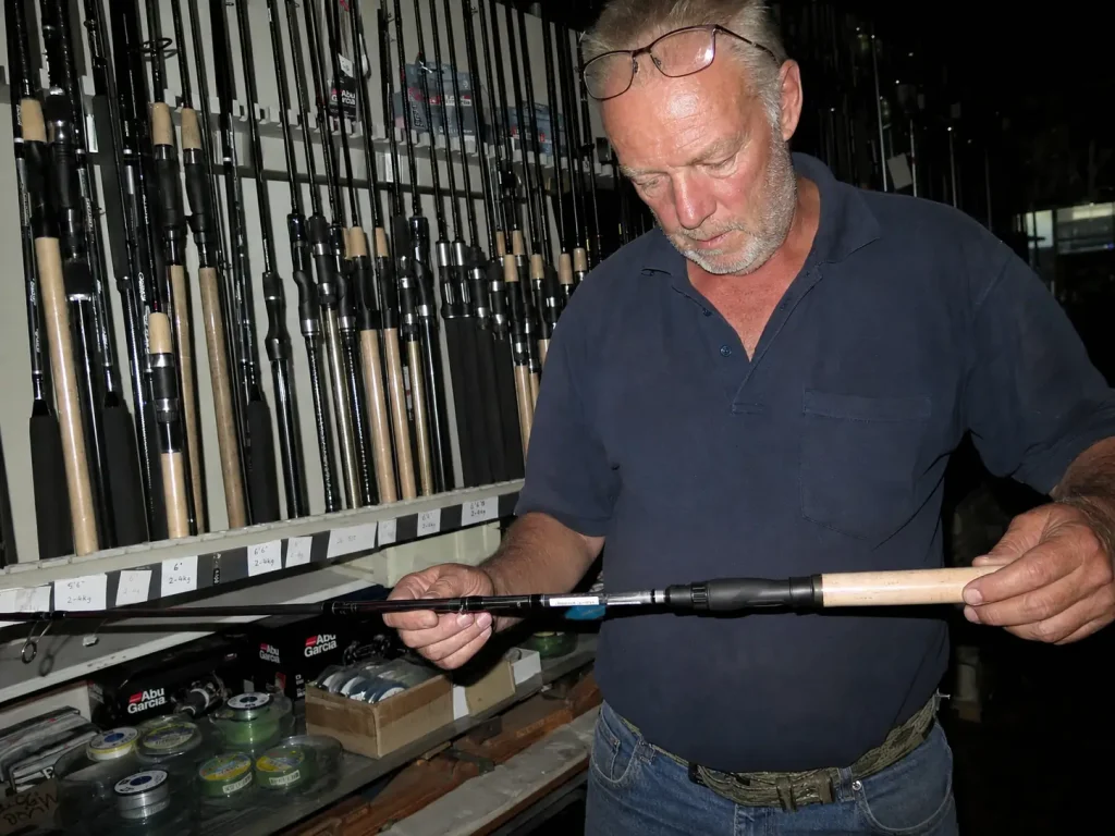 Hands spooling fresh monofilament onto a spinning reel beside the rod's spec label