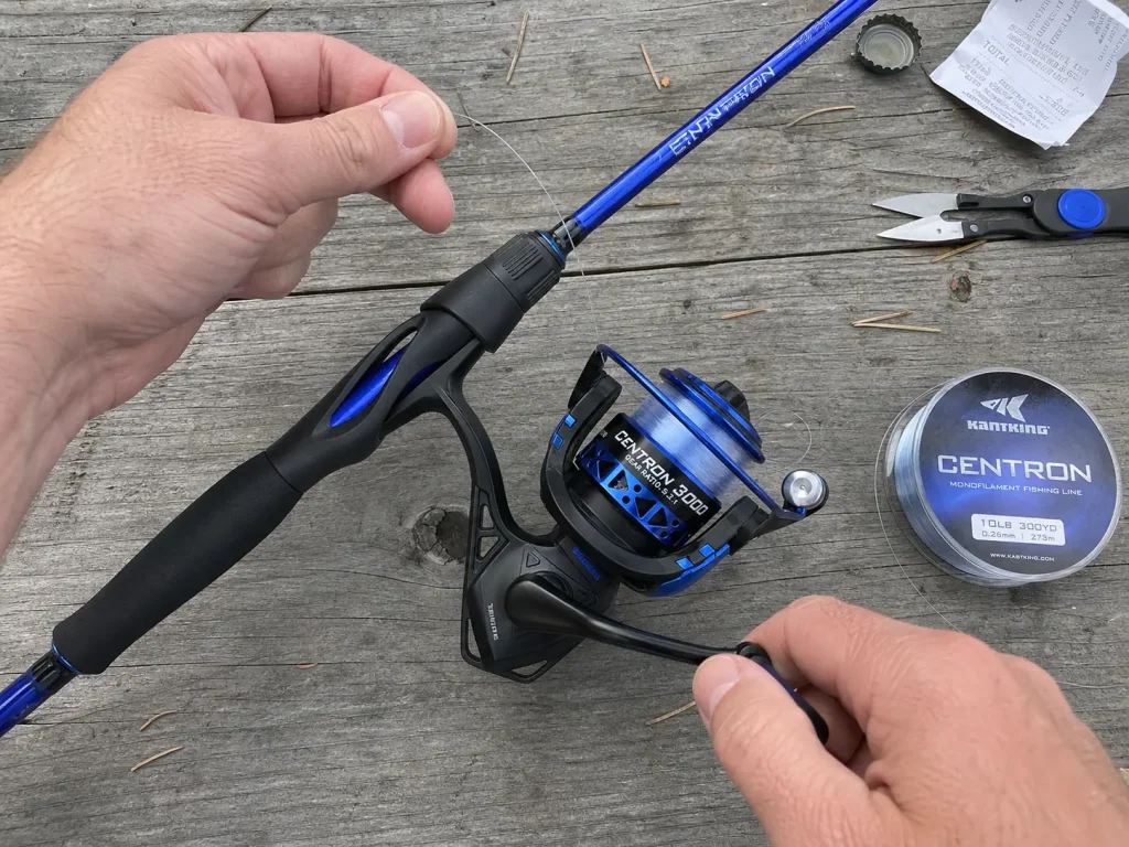 Hands spooling fresh monofilament onto a spinning reel beside the rod's spec label