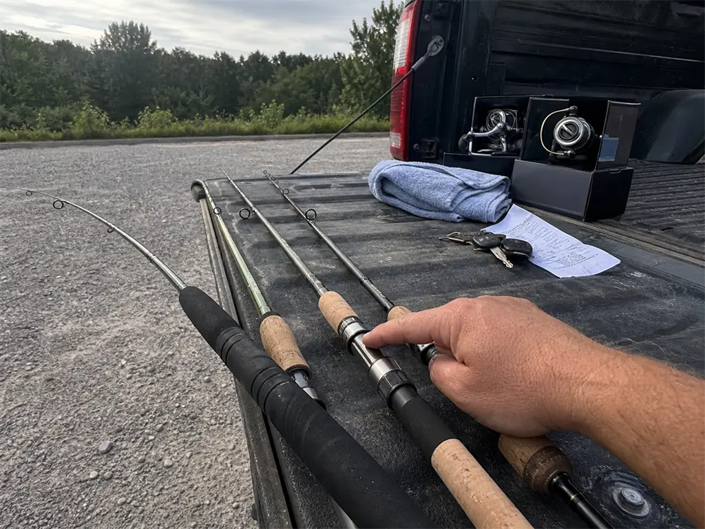 Three fishing rods from different price tiers laid on a truck tailgate for comparison